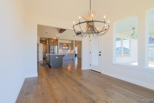 unfurnished dining area featuring baseboards, an inviting chandelier, and dark wood-style floors