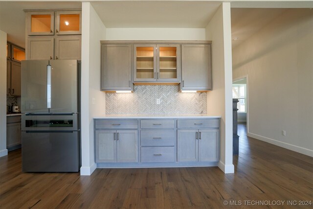 kitchen with dark hardwood / wood-style flooring, stainless steel refrigerator, and tasteful backsplash