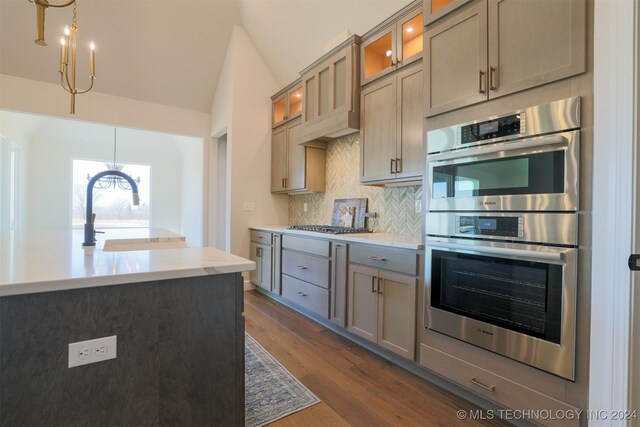 kitchen featuring sink, dark wood-type flooring, hanging light fixtures, stainless steel appliances, and decorative backsplash