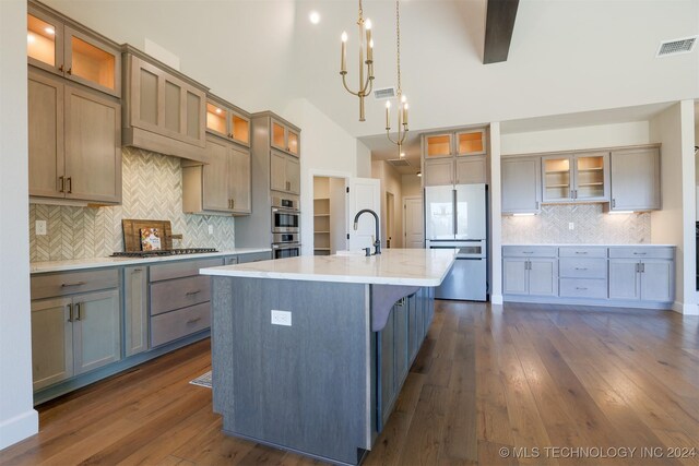 kitchen featuring hanging light fixtures, dark hardwood / wood-style flooring, backsplash, a center island with sink, and appliances with stainless steel finishes