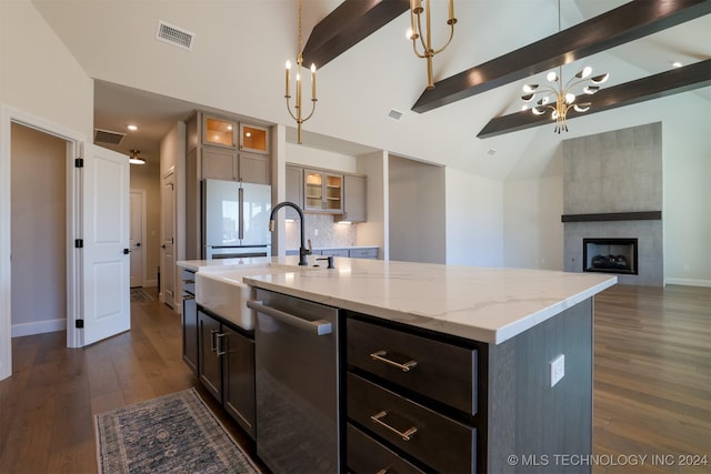 kitchen with light stone countertops, a center island with sink, dishwasher, vaulted ceiling with beams, and white fridge