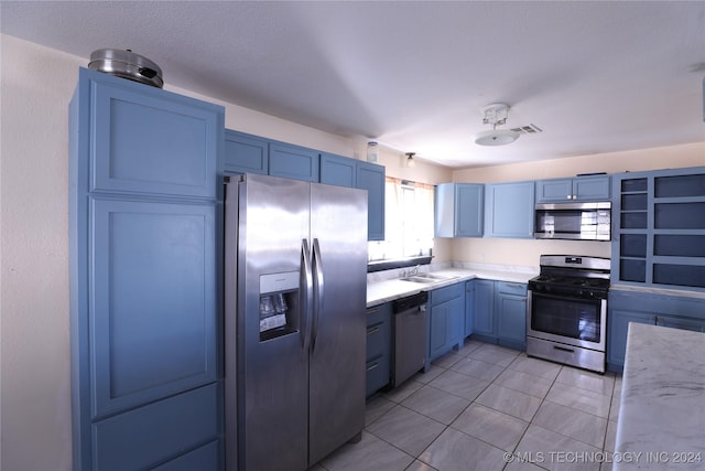 kitchen with appliances with stainless steel finishes, blue cabinets, and light tile patterned flooring