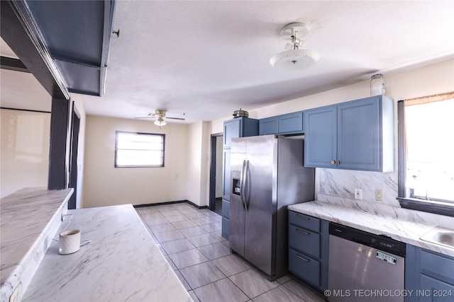 kitchen with ceiling fan, blue cabinets, a textured ceiling, light tile patterned floors, and appliances with stainless steel finishes