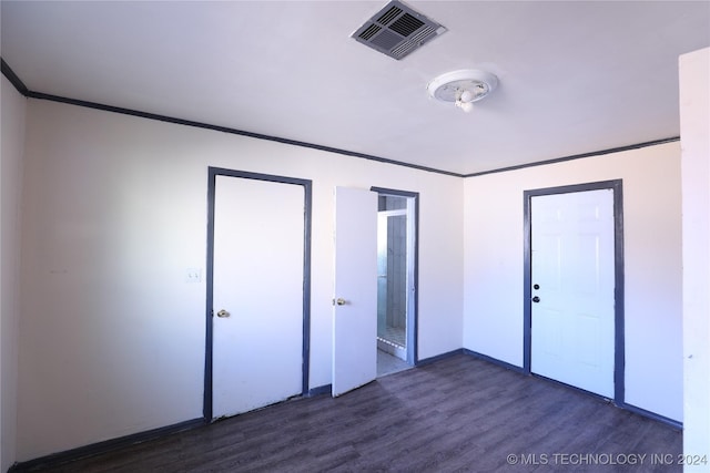 unfurnished bedroom featuring crown molding and dark wood-type flooring