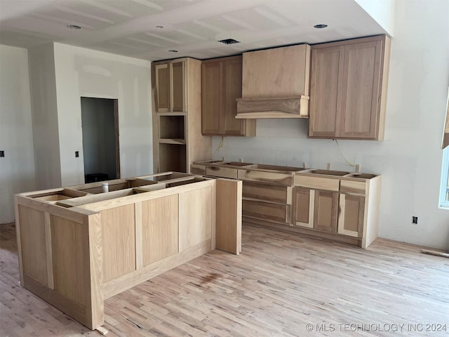 kitchen featuring sink, cooktop, light brown cabinetry, custom range hood, and light wood-type flooring