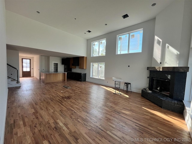 unfurnished living room featuring a fireplace, dark hardwood / wood-style flooring, and a towering ceiling