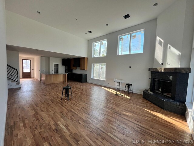 unfurnished living room with a fireplace, dark wood-type flooring, and a high ceiling