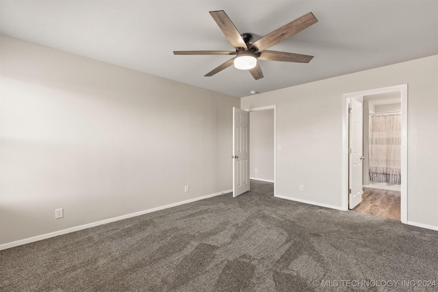 unfurnished bedroom with dark colored carpet, ensuite bath, and ceiling fan