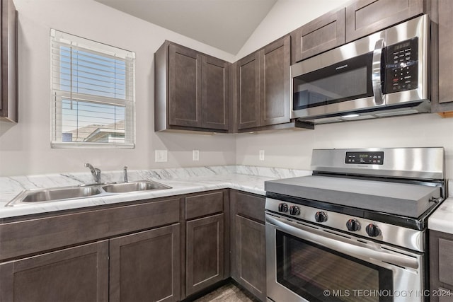 kitchen with dark brown cabinets, sink, vaulted ceiling, and appliances with stainless steel finishes