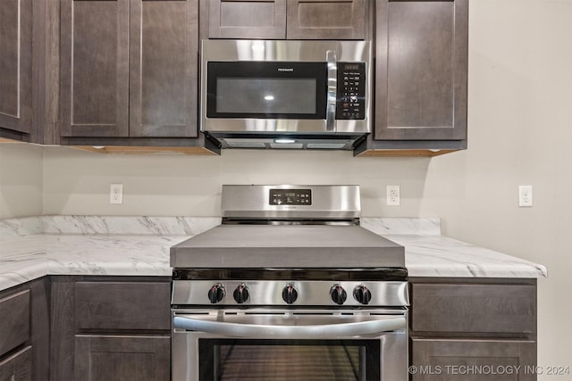 kitchen with light stone counters, dark brown cabinets, and stainless steel appliances