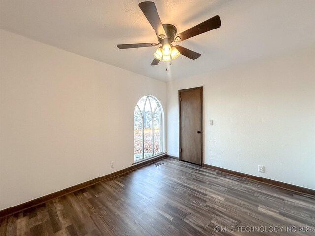 empty room with ceiling fan and dark wood-type flooring