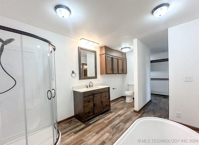 bathroom featuring wood-type flooring, vanity, toilet, and walk in shower