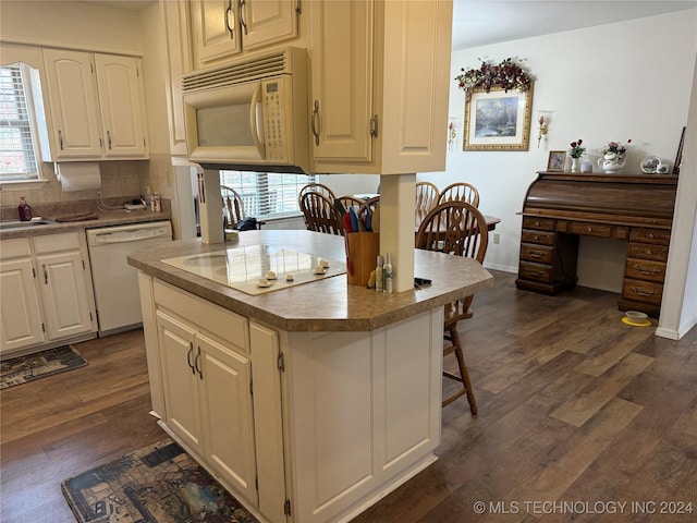 kitchen featuring a kitchen breakfast bar, white appliances, dark wood-type flooring, and sink