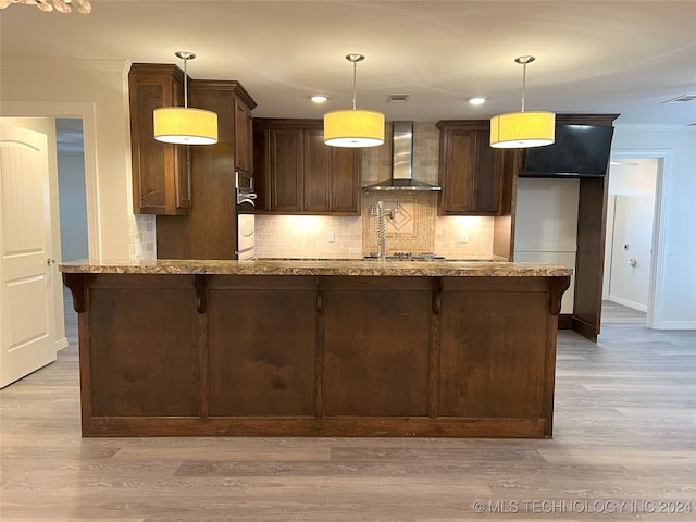 kitchen featuring light hardwood / wood-style flooring, oven, pendant lighting, and wall chimney range hood