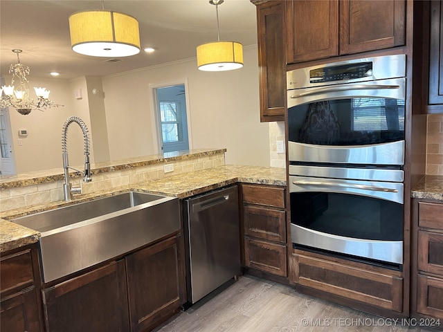 kitchen with decorative backsplash, kitchen peninsula, stainless steel appliances, and decorative light fixtures