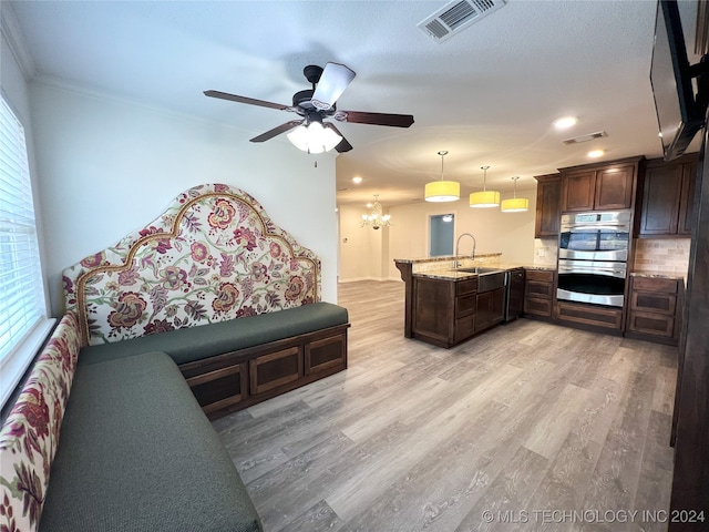 living room featuring ceiling fan with notable chandelier, light wood-type flooring, ornamental molding, and sink