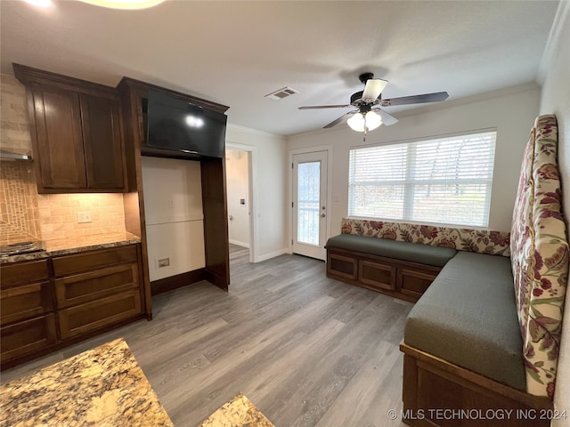 interior space featuring crown molding, ceiling fan, light wood-type flooring, tasteful backsplash, and dark brown cabinetry