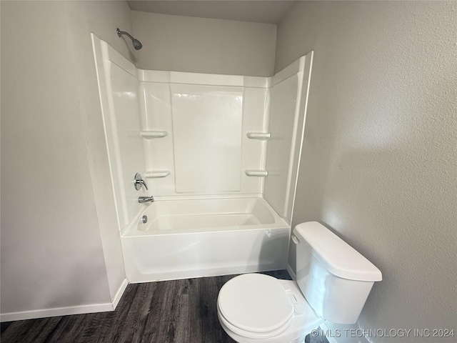 bathroom with hardwood / wood-style floors, toilet, and shower / washtub combination