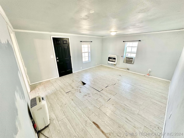 interior space featuring heating unit, a healthy amount of sunlight, a textured ceiling, and light wood-type flooring