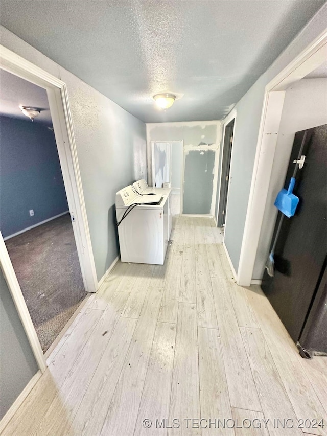 laundry room featuring a textured ceiling, washing machine and dryer, and light hardwood / wood-style flooring