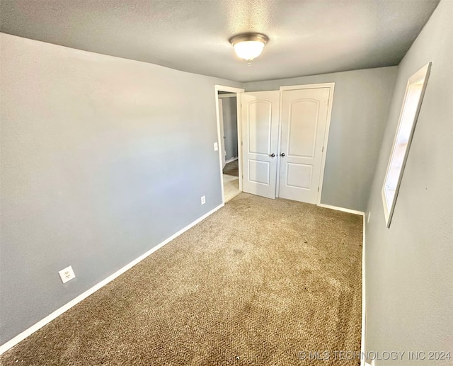 unfurnished bedroom featuring carpet floors, a textured ceiling, and a closet