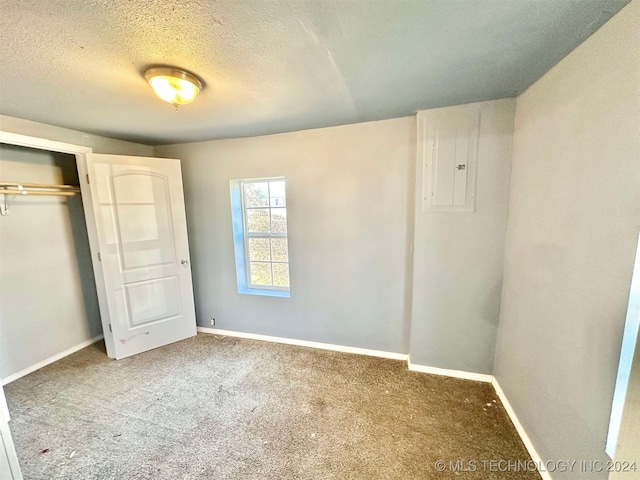 unfurnished bedroom featuring electric panel, a closet, carpet, and a textured ceiling