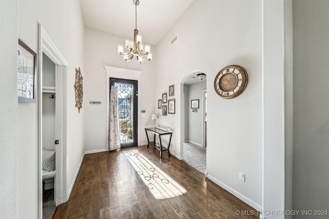 entrance foyer with a chandelier, dark wood-type flooring, and a high ceiling