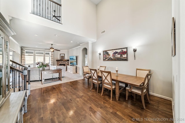 dining room with ceiling fan, wood-type flooring, a fireplace, and ornamental molding