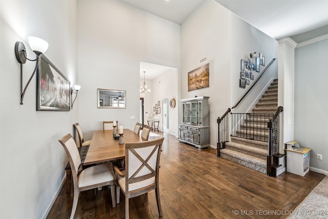 dining room with dark hardwood / wood-style flooring, a towering ceiling, and an inviting chandelier