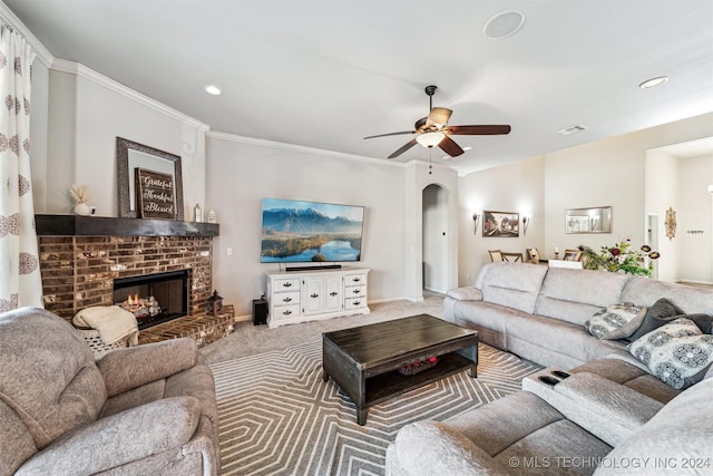 living room featuring carpet flooring, ceiling fan, ornamental molding, and a brick fireplace