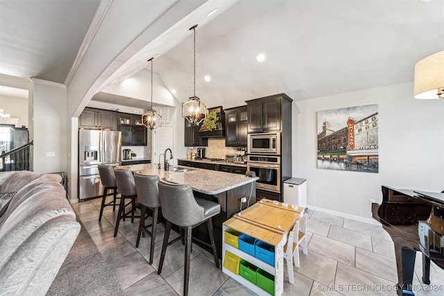 kitchen featuring appliances with stainless steel finishes, dark brown cabinets, a kitchen island with sink, sink, and hanging light fixtures