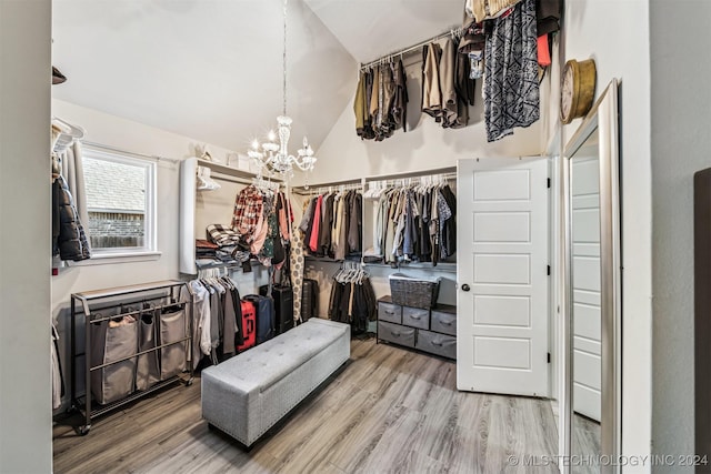 spacious closet featuring wood-type flooring, an inviting chandelier, and lofted ceiling