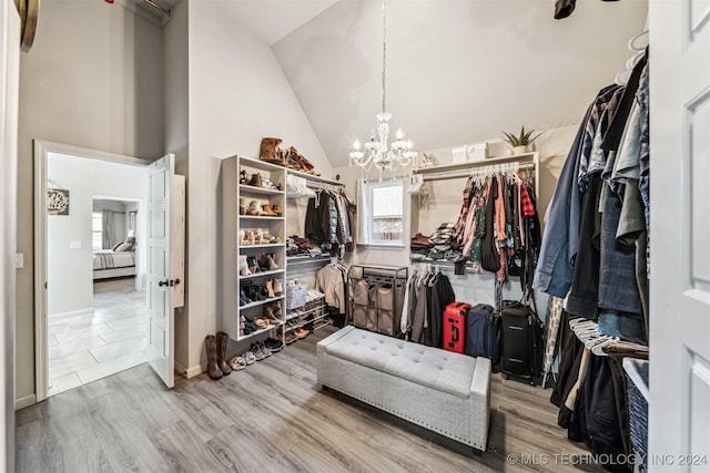 walk in closet with a chandelier, hardwood / wood-style floors, and high vaulted ceiling