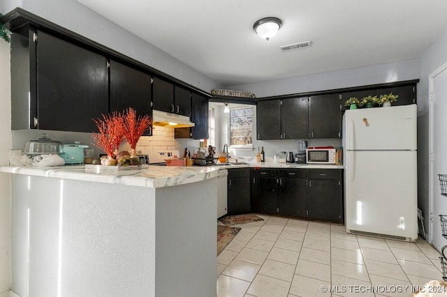 kitchen featuring kitchen peninsula, decorative backsplash, white appliances, and light tile patterned floors