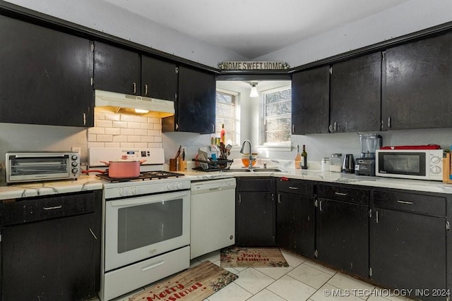 kitchen featuring backsplash, sink, light tile patterned floors, and white appliances