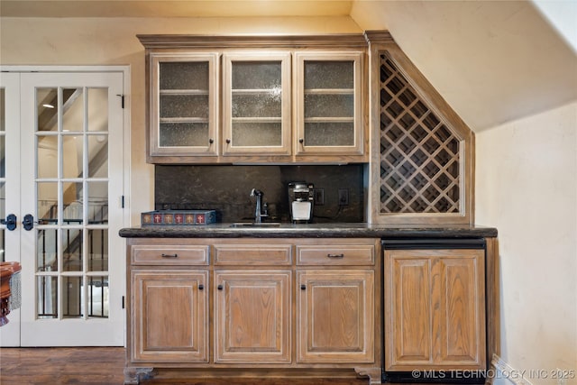 bar featuring wet bar, tasteful backsplash, wood finished floors, and a sink
