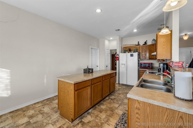 kitchen featuring white refrigerator with ice dispenser, a center island, decorative light fixtures, and sink