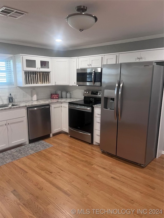 kitchen with crown molding, white cabinetry, stainless steel appliances, and light hardwood / wood-style flooring