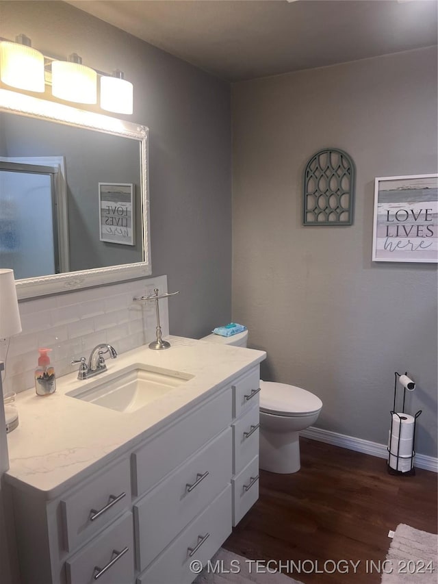 bathroom featuring hardwood / wood-style floors, vanity, tasteful backsplash, and toilet