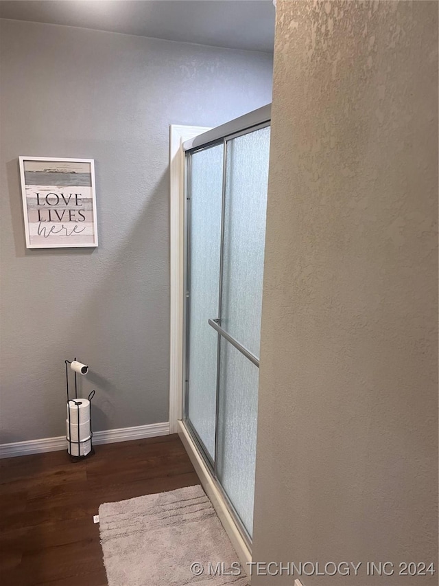 bathroom featuring an enclosed shower and wood-type flooring