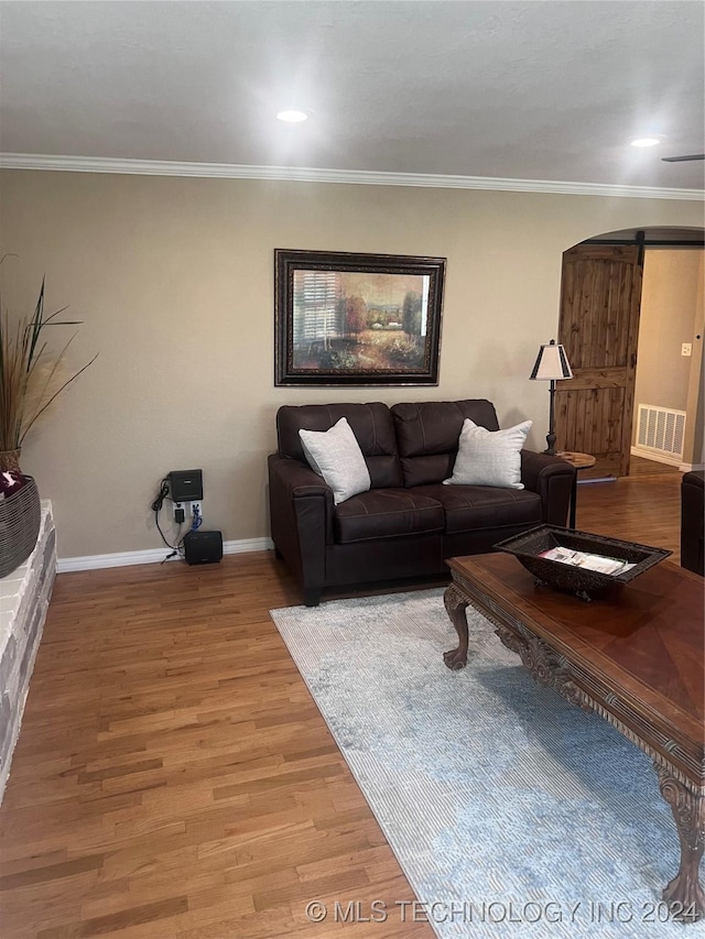 living room featuring hardwood / wood-style floors, a barn door, and crown molding