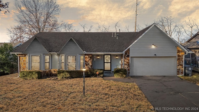 ranch-style home with a garage and a lawn