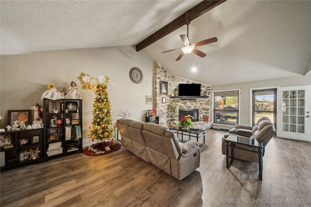 living room featuring ceiling fan, vaulted ceiling with beams, hardwood / wood-style floors, a textured ceiling, and a fireplace