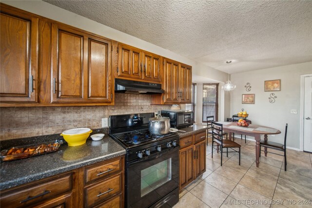 kitchen with pendant lighting, dark stone counters, black appliances, decorative backsplash, and light tile patterned floors