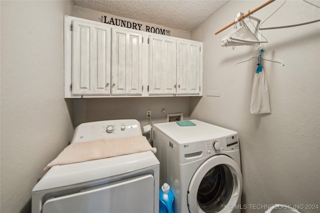 laundry room with cabinets, a textured ceiling, and washer and dryer