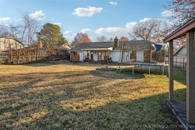 back of property featuring a trampoline and a lawn