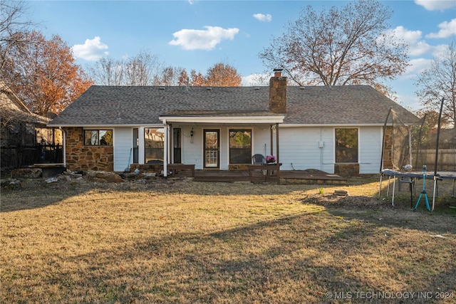 rear view of house featuring covered porch, a yard, and a trampoline