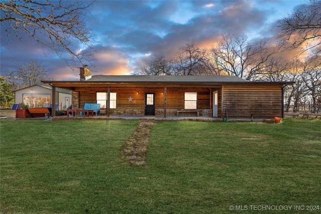 back house at dusk featuring a lawn