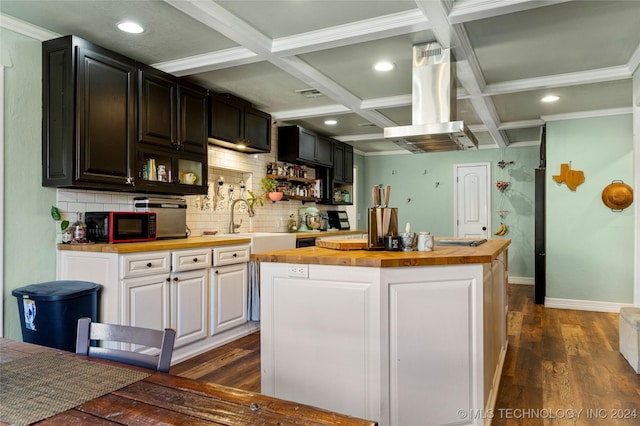 kitchen with island exhaust hood, coffered ceiling, a center island, butcher block countertops, and white cabinetry