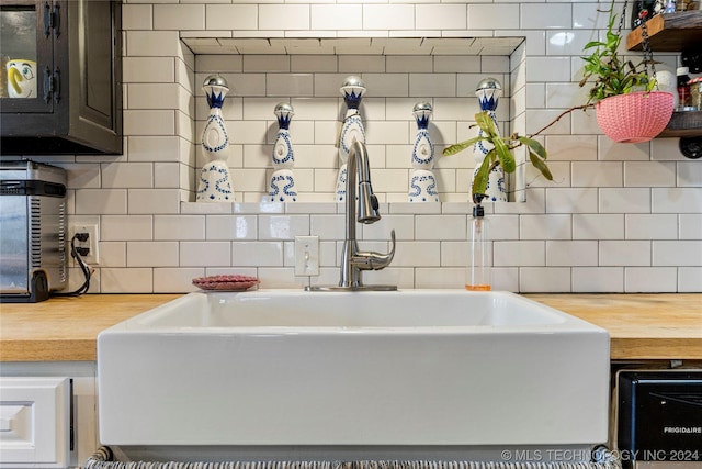 kitchen with wood counters, backsplash, and sink